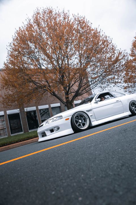 Low-angle rolling shot of Aum Sung’s white 1992 Lexus SC400 featuring BN Sports widebody styling and Work Meister wheels.