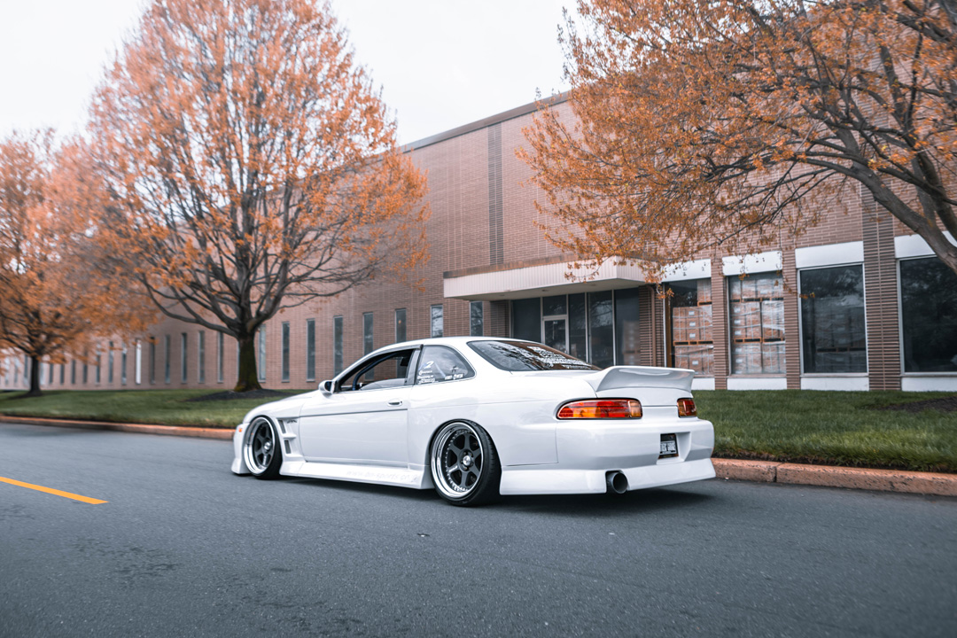 Rear three-quarter shot of Aum Sung’s white 1992 Lexus SC400 featuring BN Sports widebody styling and deep-dish Work Meister wheels.