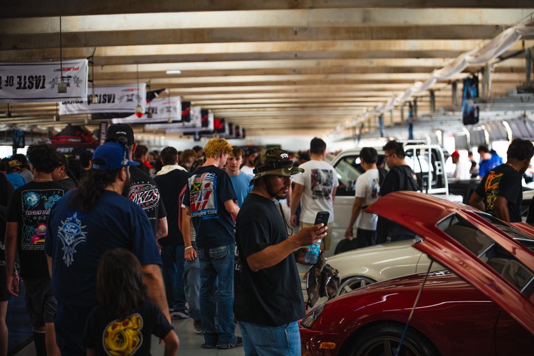 FuelFest attendees walking through the paddock and garage areas at Texas Motor Speedway during the Dallas-Fort Worth event.