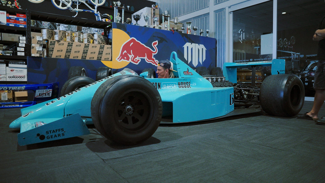 Driver seated in a teal March Formula One chassis inside a workshop during the FORMIDABUL drift car build.