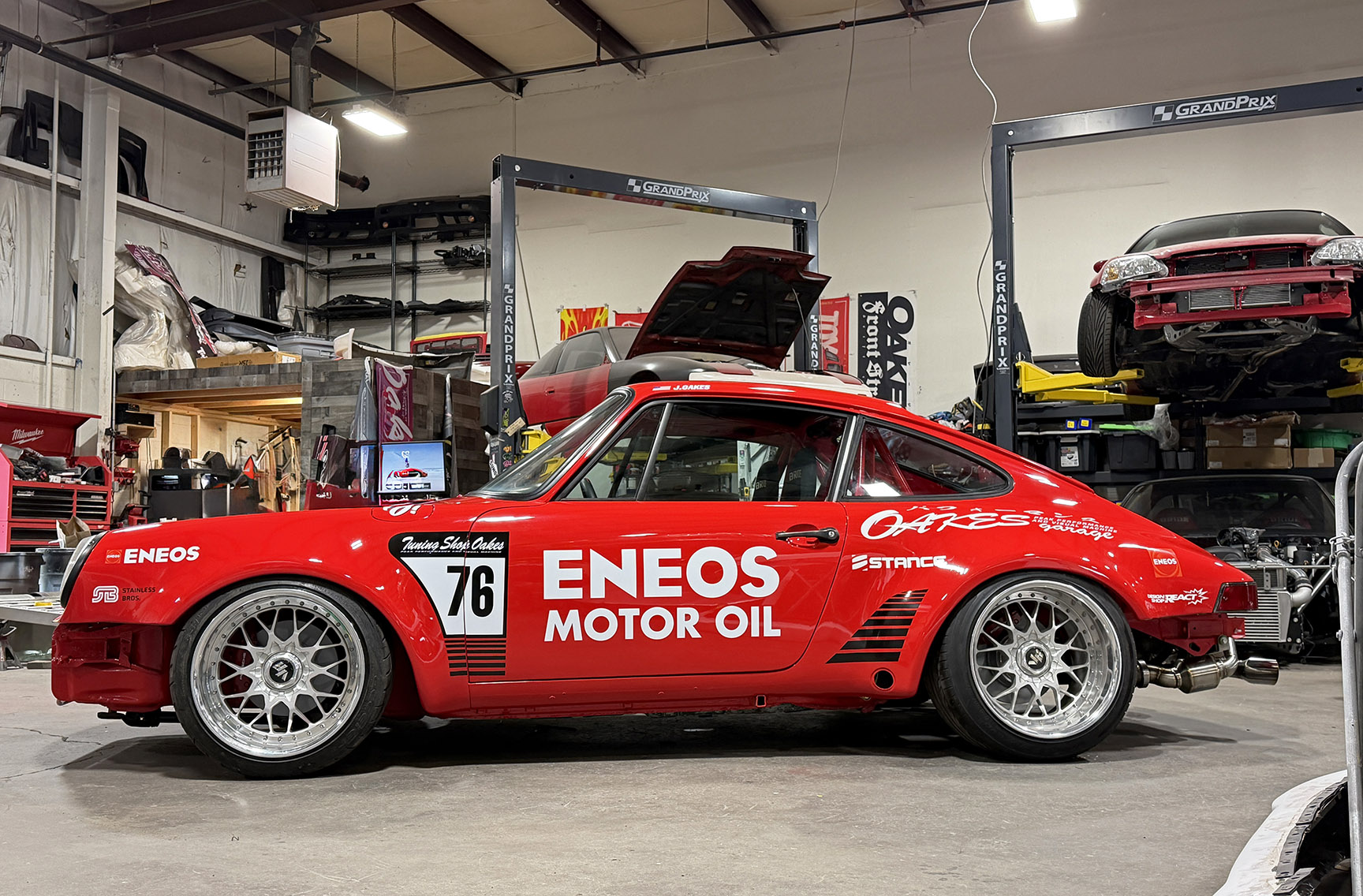 Jimmy Oakes’ red ENEOS-backed Porsche 911 SC Porrari shown in full side profile inside the shop.