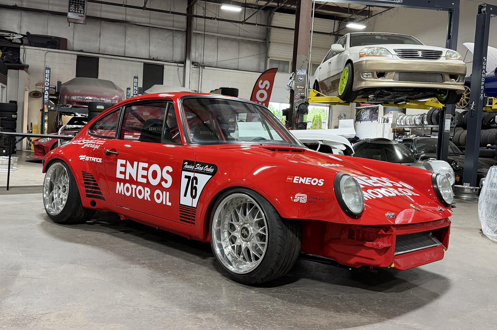 Jimmy Oakes’ red ENEOS-backed Porsche 911 SC Porrari shown in side profile inside a shop before its Formula DRIFT Connecticut debut.