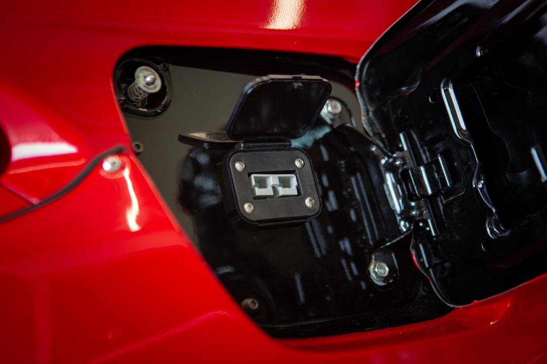 Close-up of the hidden trickle charger port behind the gas cap on Jon Erickson’s red 2011 Subaru STi.