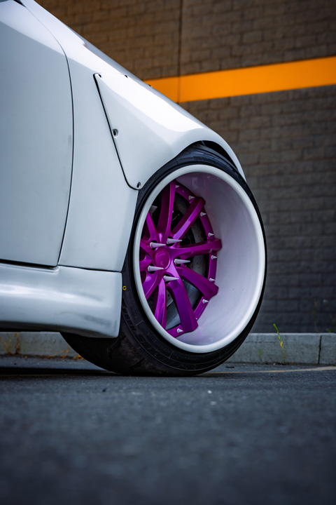 Close-up of Jordyn Brazeau’s 2006 Infiniti G35 showing the front widebody fender, deep-dish pink Weds Kranze Vishnu wheel, and stretched tire fitment.