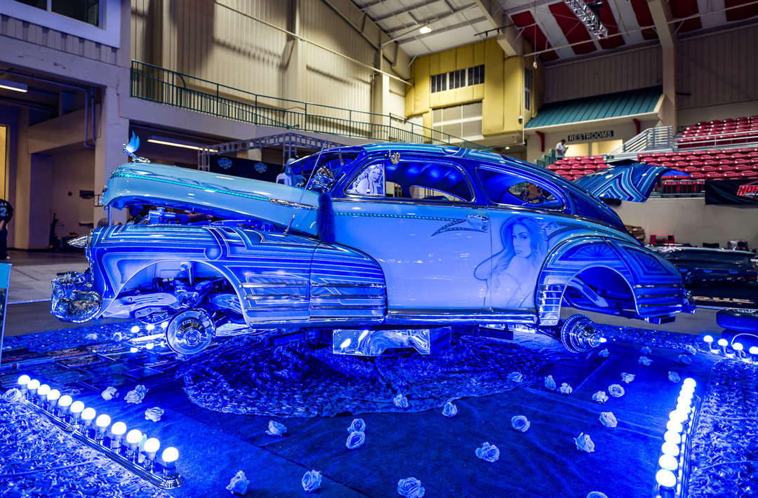 Blue custom lowrider bomb with detailed paint, chrome, and lighting on display at Lowrider Super Show Charlotte 2026.