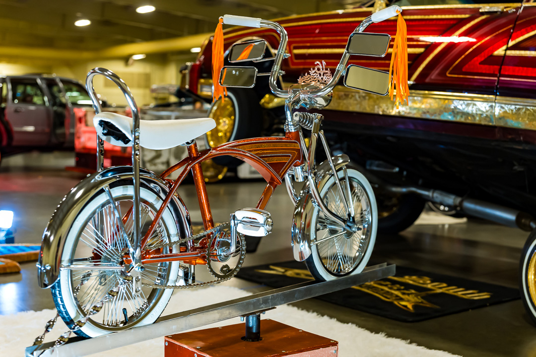 Custom lowrider bicycle with chrome details, mirrors, and orange tassels on display at Lowrider Super Show Charlotte 2026.