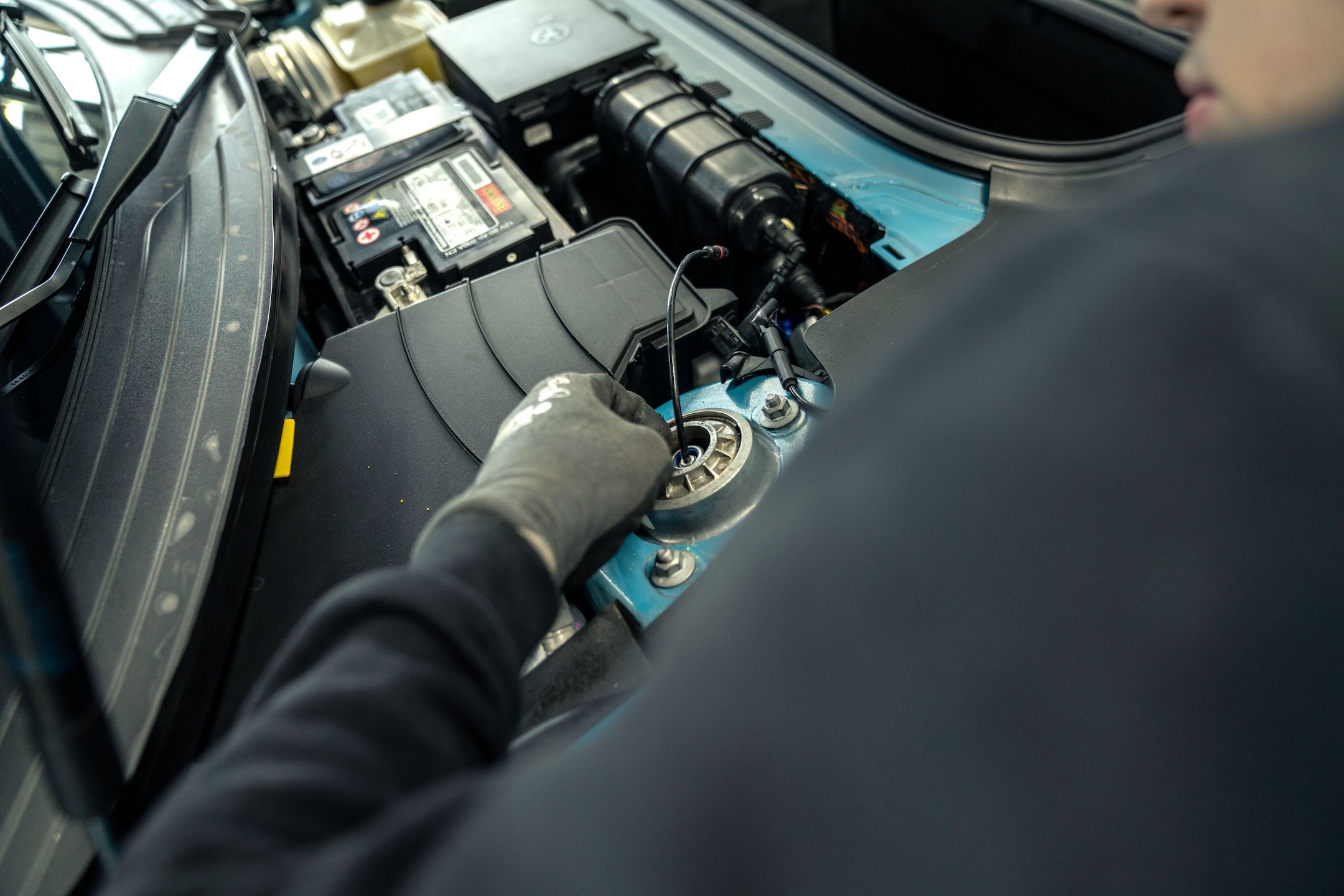 Technician connecting the KW DDC Plug & Play coilover suspension to the factory PASM wiring on a Porsche 911 991.