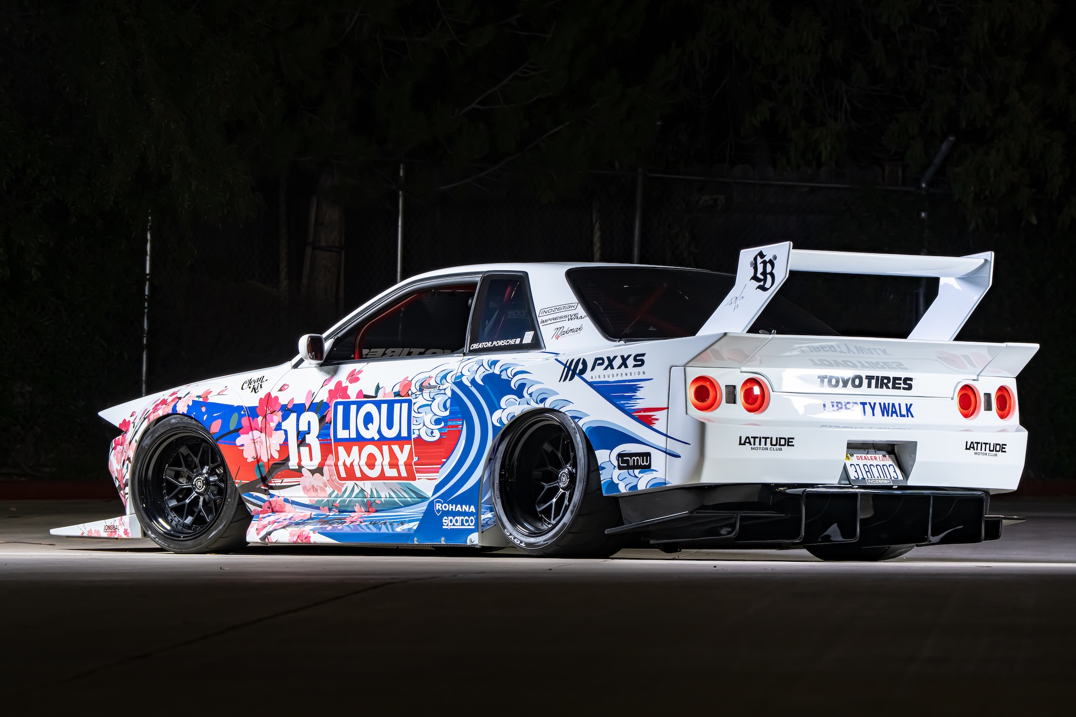 Rear three-quarter view of Osmond Seangsuwan’s 1990 Nissan Skyline GT-R showing the Liberty Walk LB-Kaido widebody kit, LIQUI MOLY livery, Rohana wheels, GT-style wing, and rear diffuser.