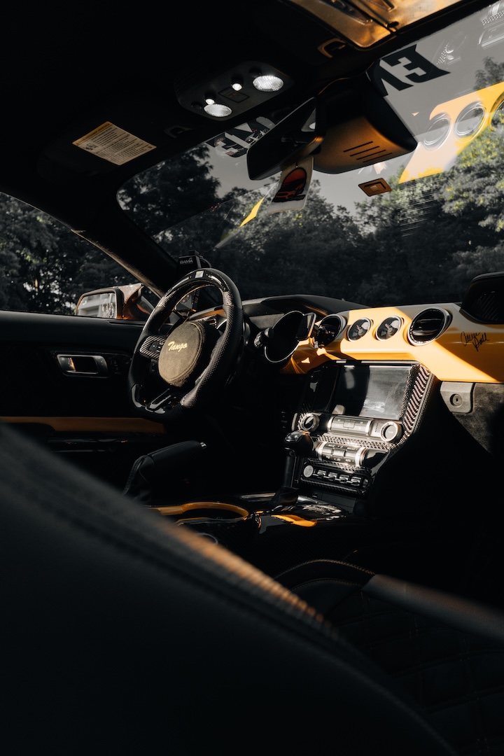 Mussi Hussain’s Cyber Orange 2022 Ford Mustang GT with Robot Craftsman widebody aero, Air Lift suspension, Work Gnosis wheels, custom lighting, carbon-fiber details, and reworked interior and trunk setup.