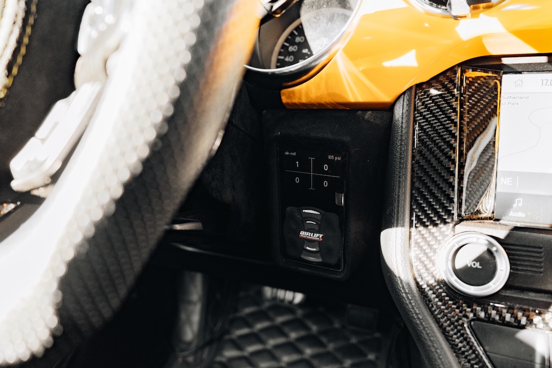 Mussi Hussain’s Cyber Orange 2022 Ford Mustang GT with Robot Craftsman widebody aero, Air Lift suspension, Work Gnosis wheels, custom lighting, carbon-fiber details, and reworked interior and trunk setup.
