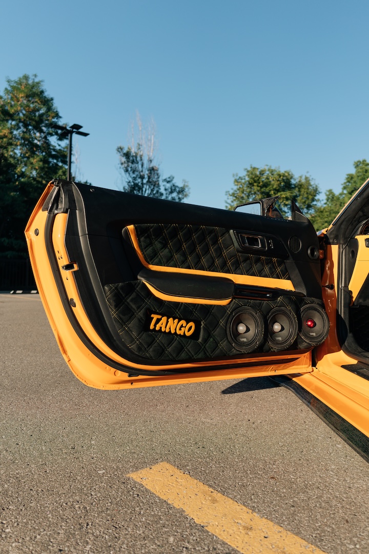 Mussi Hussain’s Cyber Orange 2022 Ford Mustang GT with Robot Craftsman widebody aero, Air Lift suspension, Work Gnosis wheels, custom lighting, carbon-fiber details, and reworked interior and trunk setup.