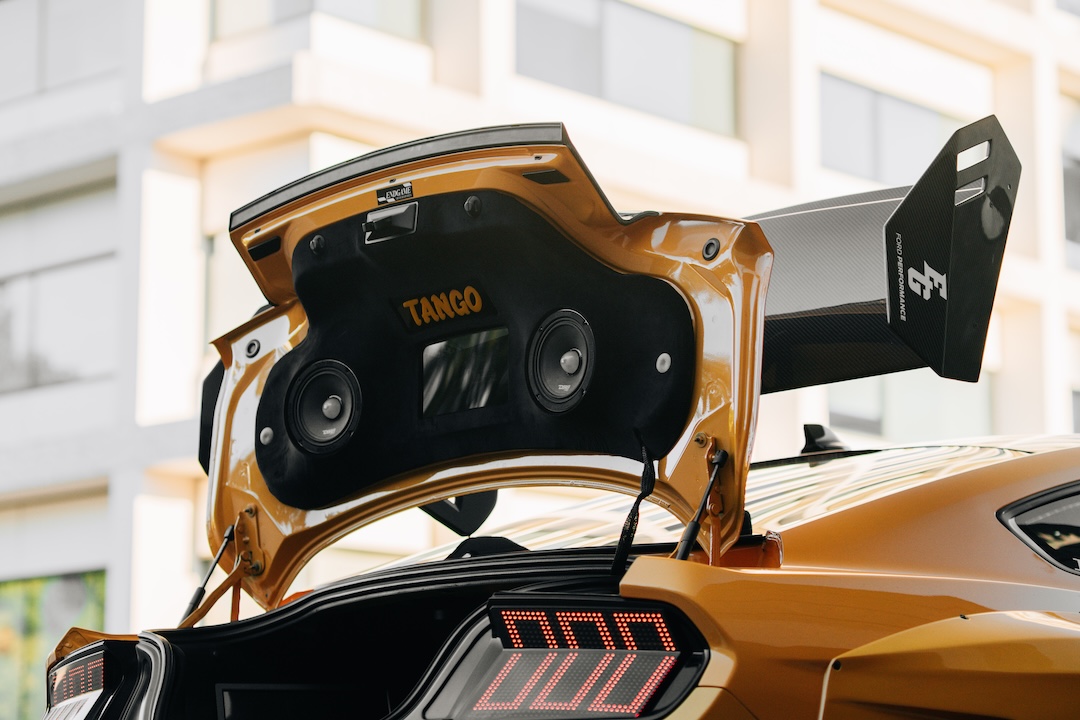 Mussi Hussain’s Cyber Orange 2022 Ford Mustang GT with Robot Craftsman widebody aero, Air Lift suspension, Work Gnosis wheels, custom lighting, carbon-fiber details, and reworked interior and trunk setup.
