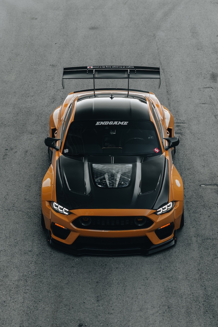 Mussi Hussain’s Cyber Orange 2022 Ford Mustang GT with Robot Craftsman widebody aero, Air Lift suspension, Work Gnosis wheels, custom lighting, carbon-fiber details, and reworked interior and trunk setup.
