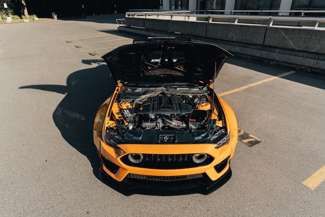 Mussi Hussain’s Cyber Orange 2022 Ford Mustang GT with Robot Craftsman widebody aero, Air Lift suspension, Work Gnosis wheels, custom lighting, carbon-fiber details, and reworked interior and trunk setup.