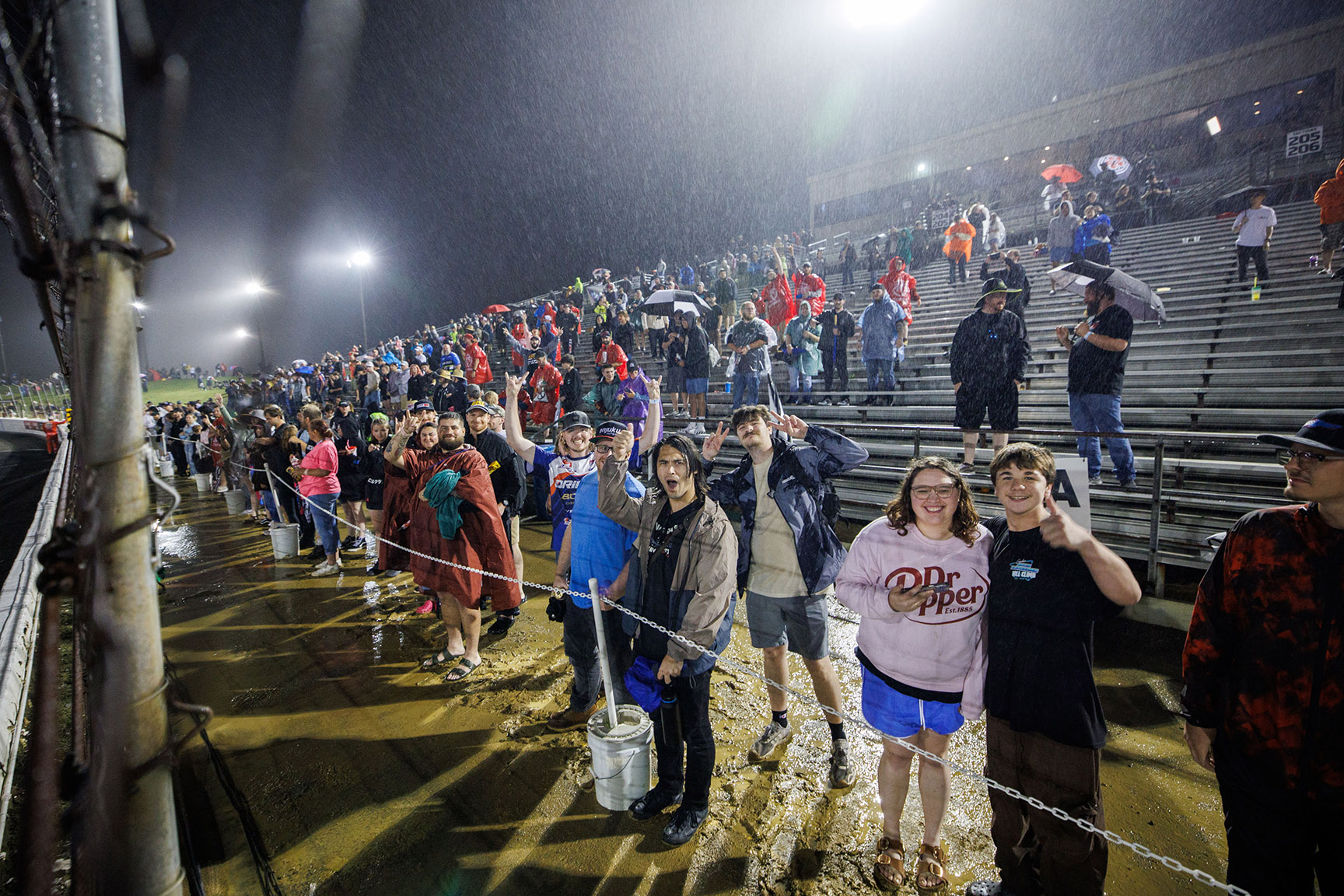 Fans stand in heavy rain near the grandstands during Formula DRIFT Indianapolis at Lucas Oil Indianapolis Raceway Park in 2026.