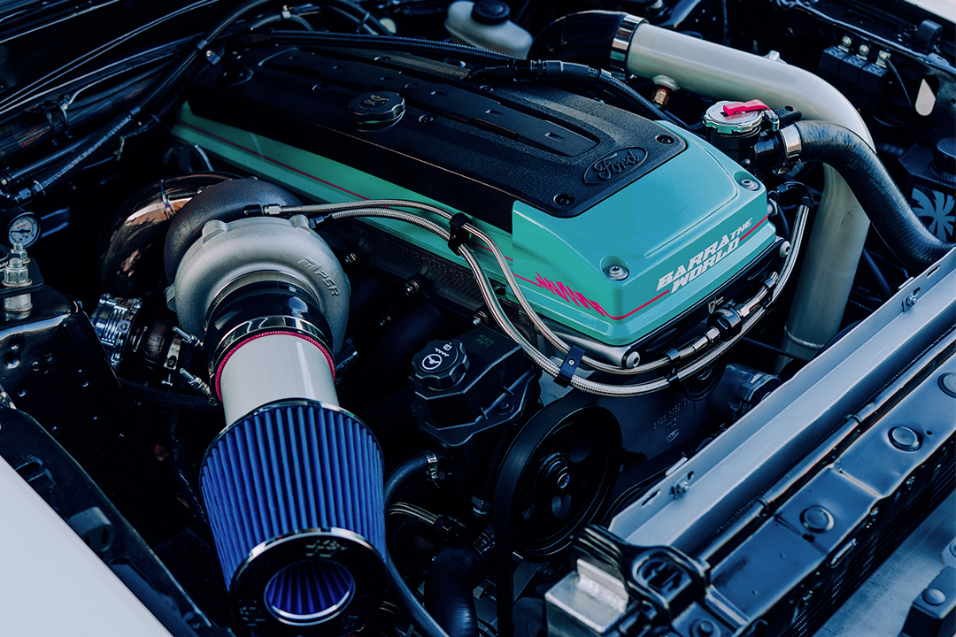 Engine bay detail of Regan McLaughlin’s 1988 Ford Mustang GT TimeFox showing the Ford Barra 4.0L inline-six swap, turbo setup, custom color-matched valve cover, intake, and clean tucked engine bay.