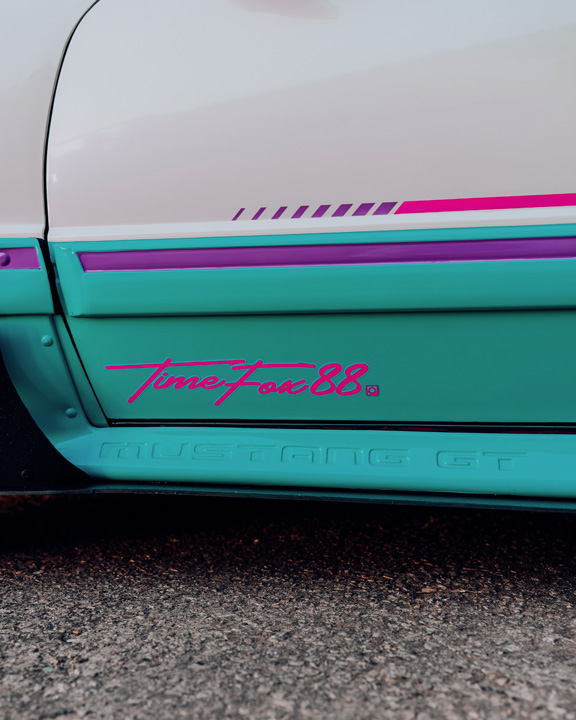 Regan McLaughlin’s 1988 Ford Mustang GT TimeFox with custom multi-tone paint, Ford Barra turbo swap, wide fiberglass fenders, retro Foxbody styling, HaloBLK wheel covers, custom interior, and nostalgic audio details.
