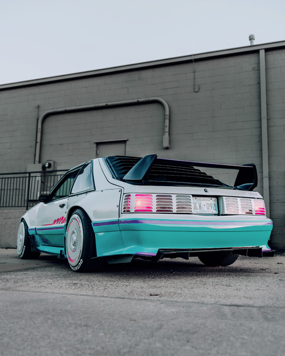 Regan McLaughlin’s 1988 Ford Mustang GT TimeFox with custom multi-tone paint, Ford Barra turbo swap, wide fiberglass fenders, retro Foxbody styling, HaloBLK wheel covers, custom interior, and nostalgic audio details.
