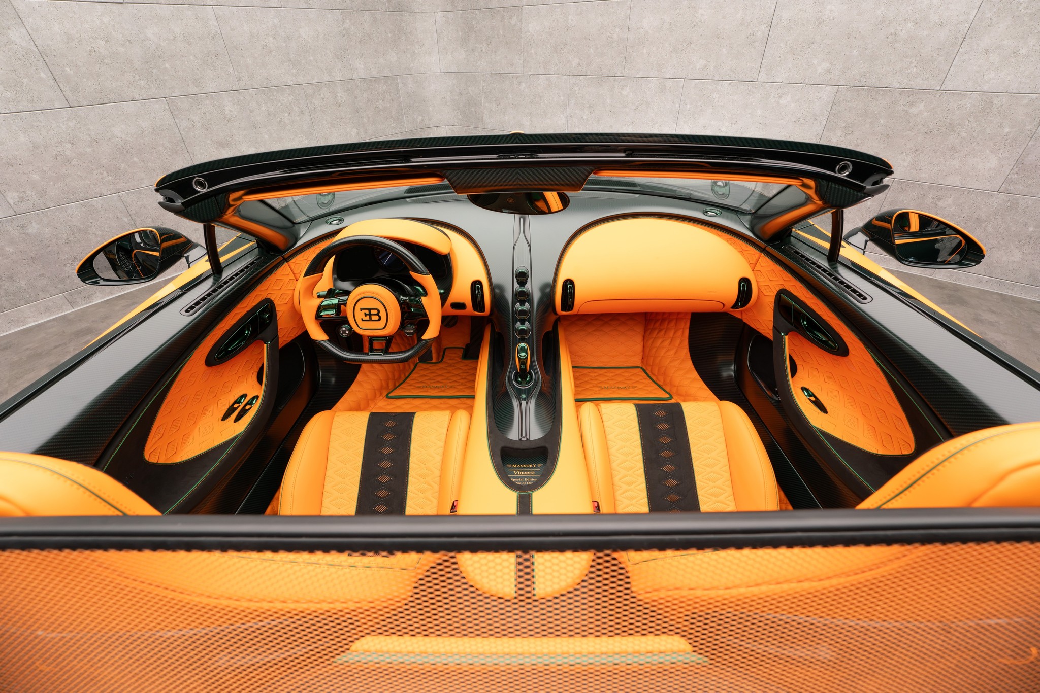MANSORY Vincerò Bugatti Mistral-based one-off interior shown from above with orange leather, exposed carbon fiber trim, and custom MANSORY detailing.