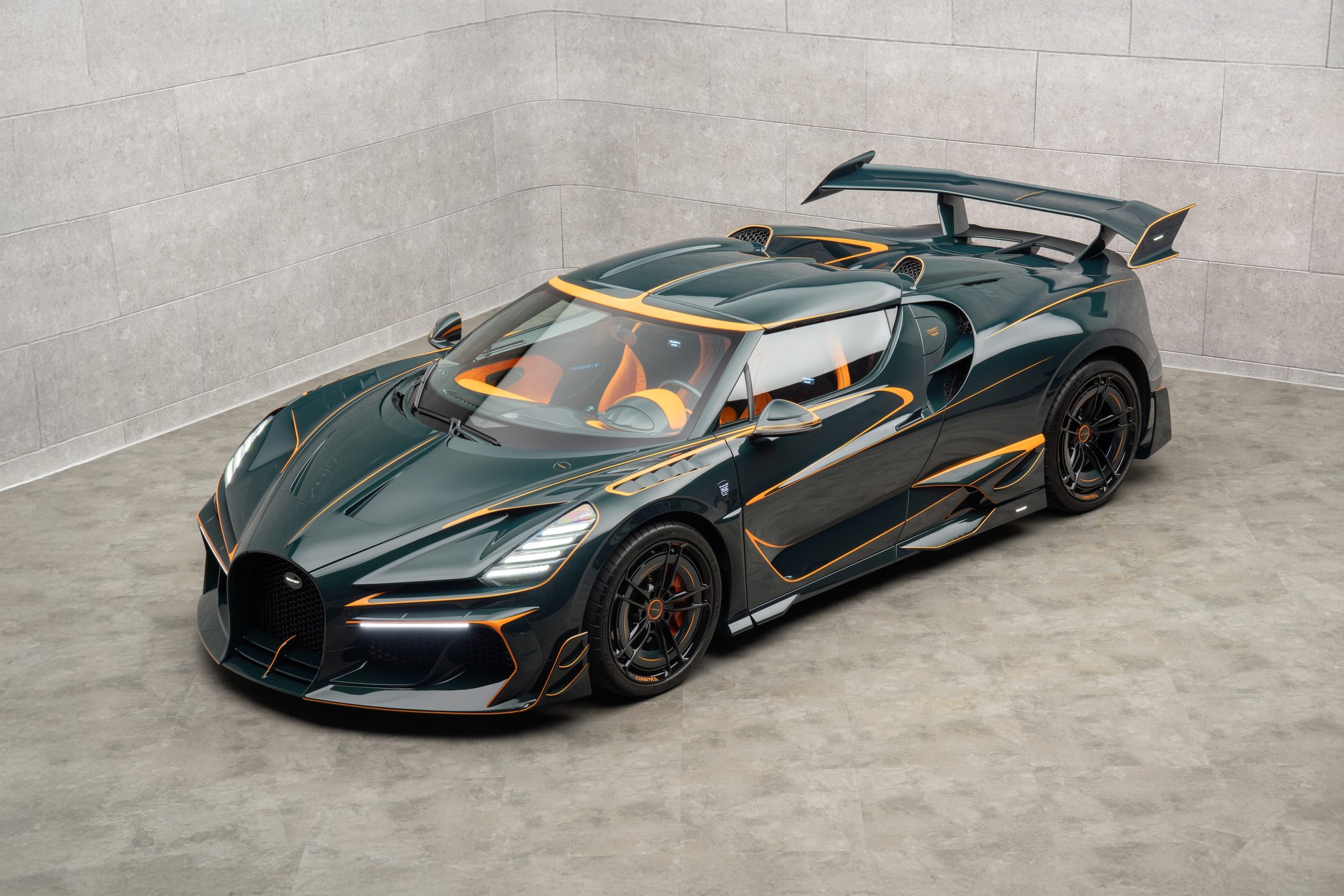 MANSORY Vincerò Bugatti Mistral-based one-off shown from the front three-quarter angle with dark green bodywork, orange accents, and a large rear wing.