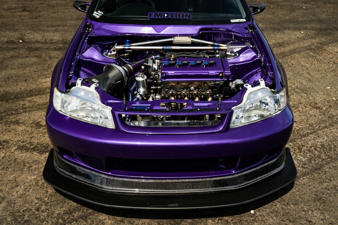 Front view of Brandon Elste’s 1996 Honda Civic showing its Honda Domani front-end conversion, open B16A2 engine bay, Plum Crazy paint, and Racebred front splitter.