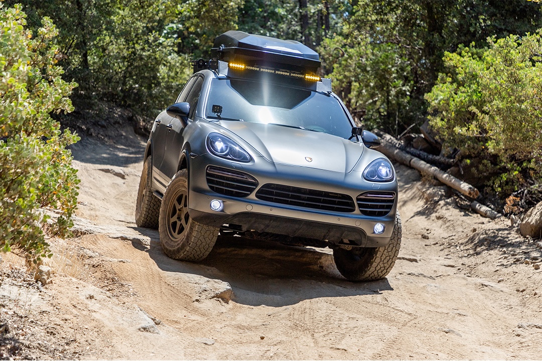Porsche Cayenne 9PA equipped with KW V3 Safari Style suspension driving on a rough off-road trail.