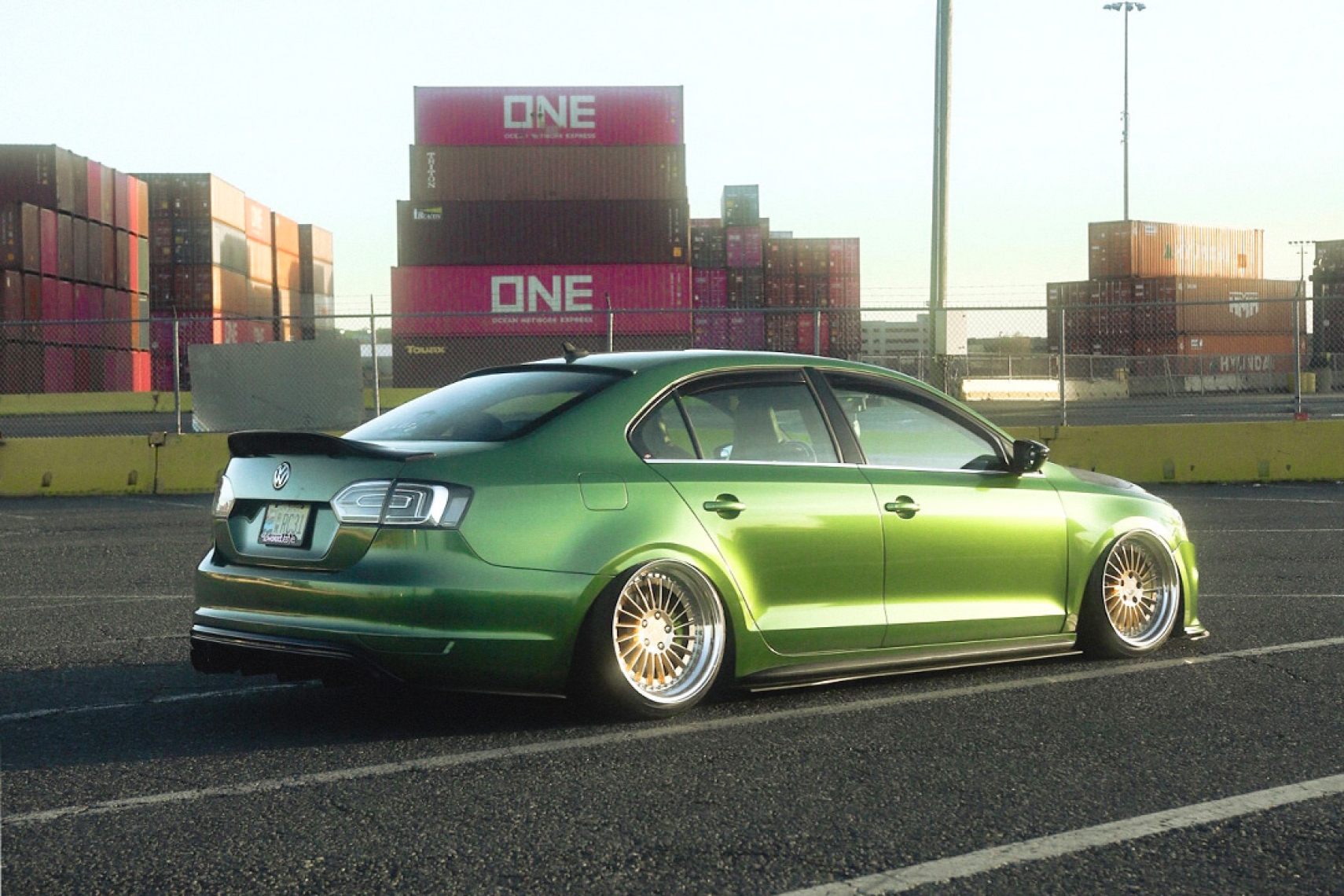 Wilson Paulino’s Olive Green 2013 Volkswagen GLI aired out on Rotiform IND-T three-piece wheels in a rear three-quarter view.